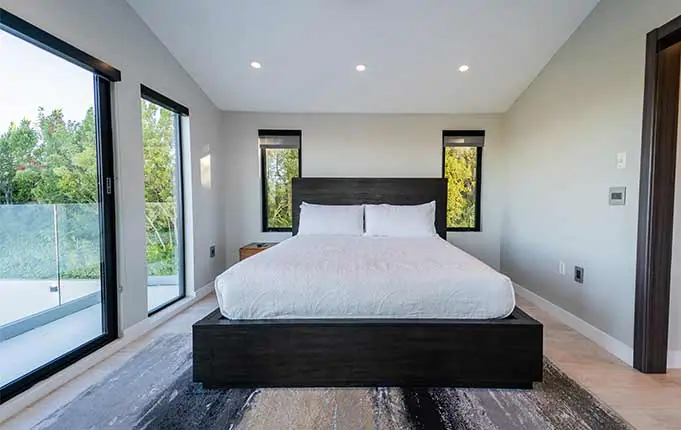 Finished primary bedroom with hardwood floors and large windows