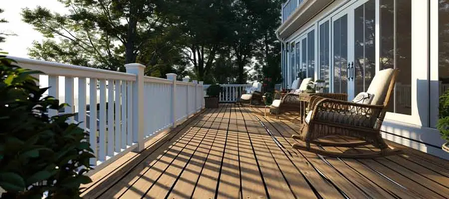 Long wood deck with white railings along a house