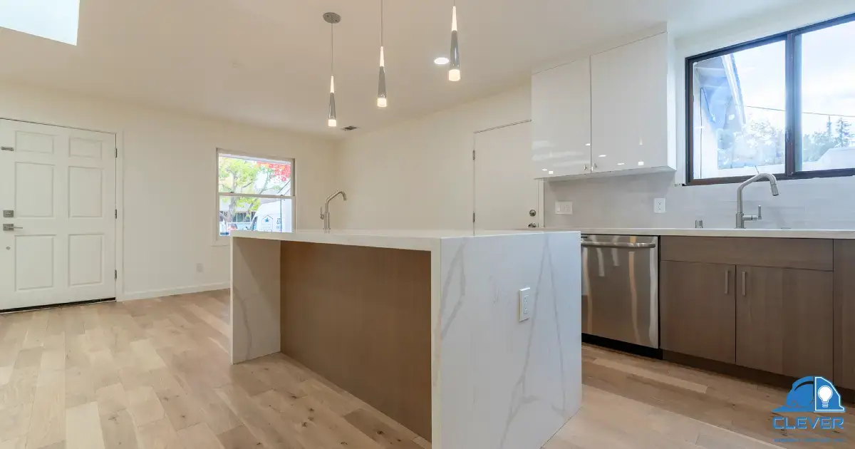 Open-plan kitchen with a waterfall quartz island, skylights and wood cabinetry