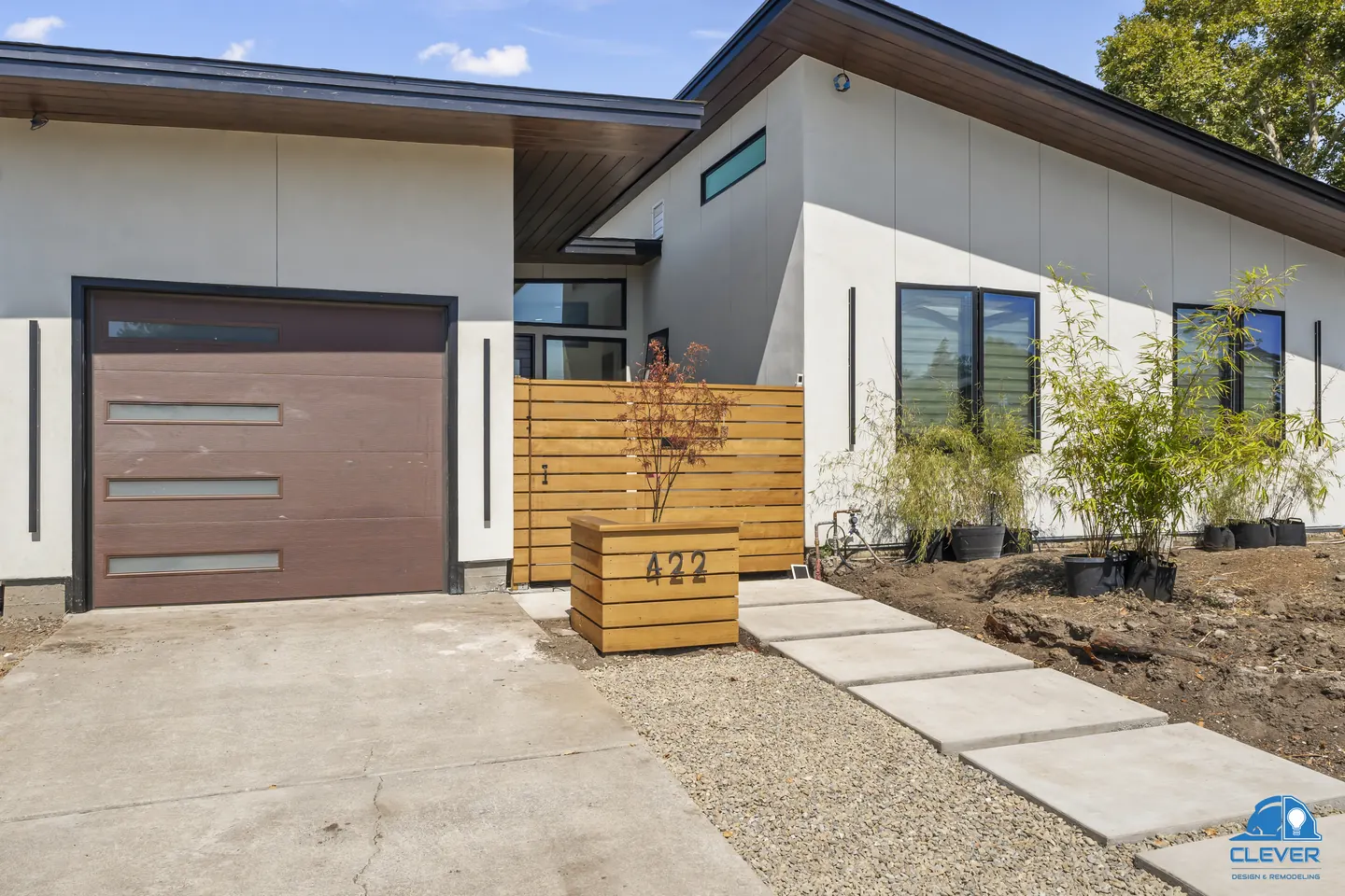Front of a modern single-story home with white stucco, a brown garage door and a horizontal cedar fence, modern home in Santa Clara, CA