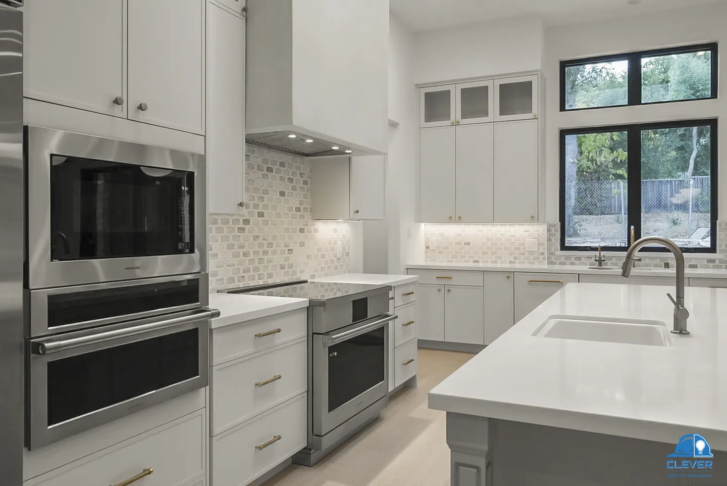 Double wall ovens, a stainless range and a mosaic tile backsplash beside a black-framed window, whole-home remodel in Palo Alto, CA