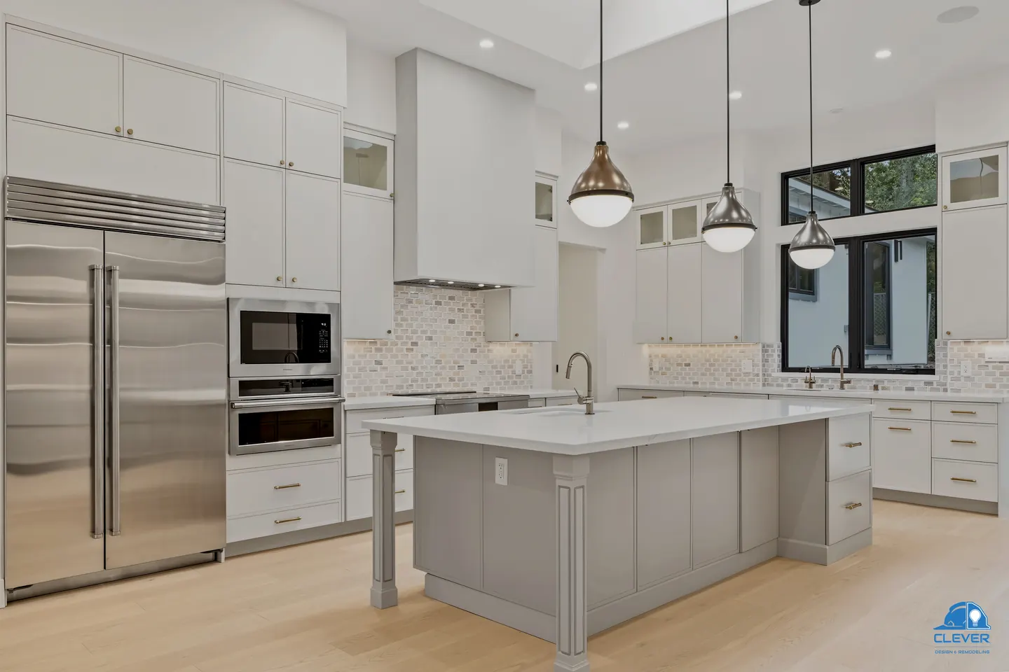 Kitchen with a built-in stainless refrigerator, double wall ovens and a gray island under brass pendants, whole-home remodel in Saratoga, CA