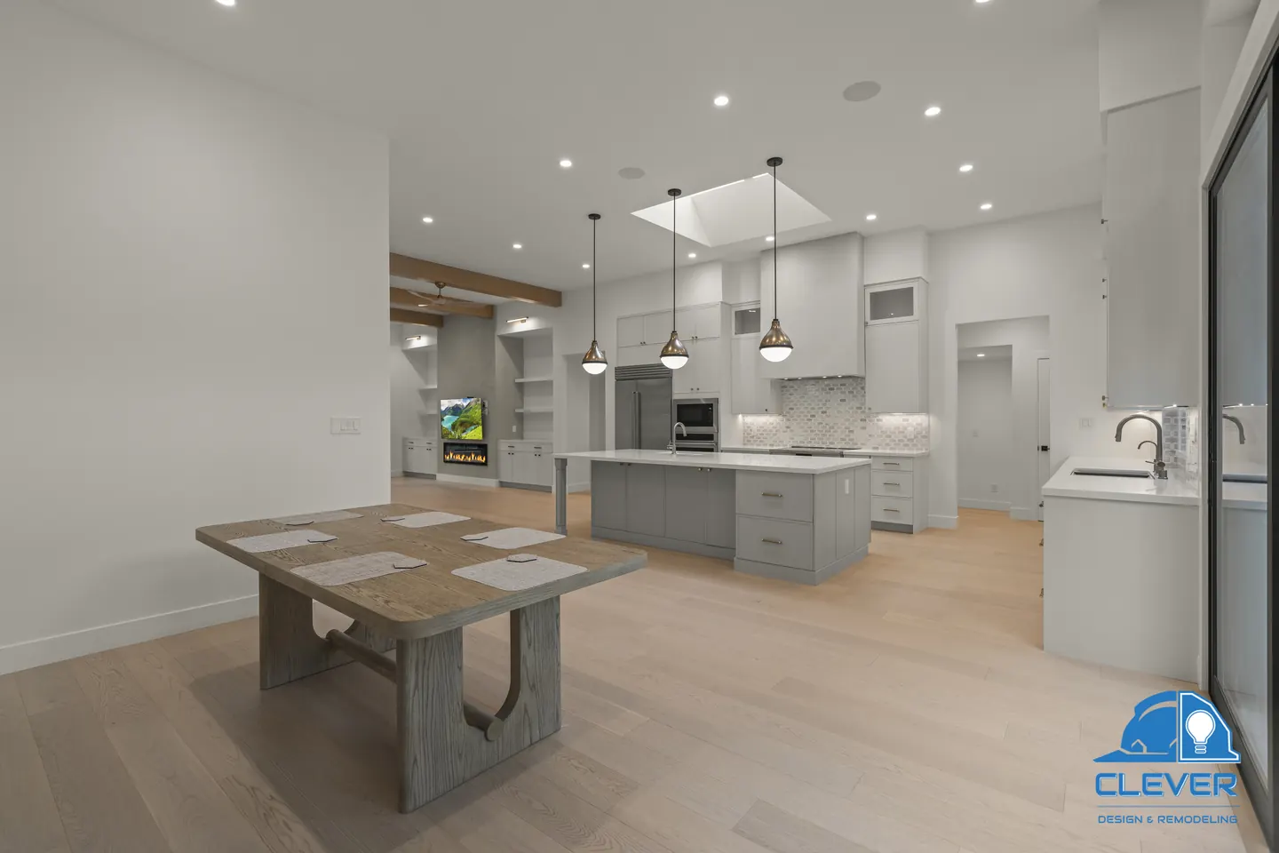 Dining area open to the kitchen island, with the linear fireplace lit in the great room beyond, whole-home remodel in Saratoga, CA
