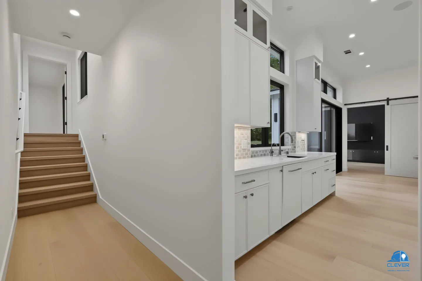 White oak stairs off a hall beside the kitchen, with a barn door to the media room, whole-home remodel in Saratoga, CA