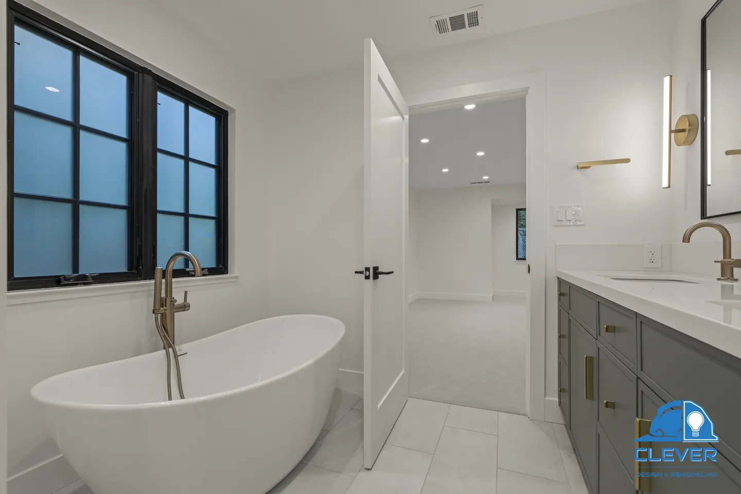 Freestanding soaking tub with a brass floor-mount faucet beside a black-framed window, whole-home remodel in Saratoga, CA