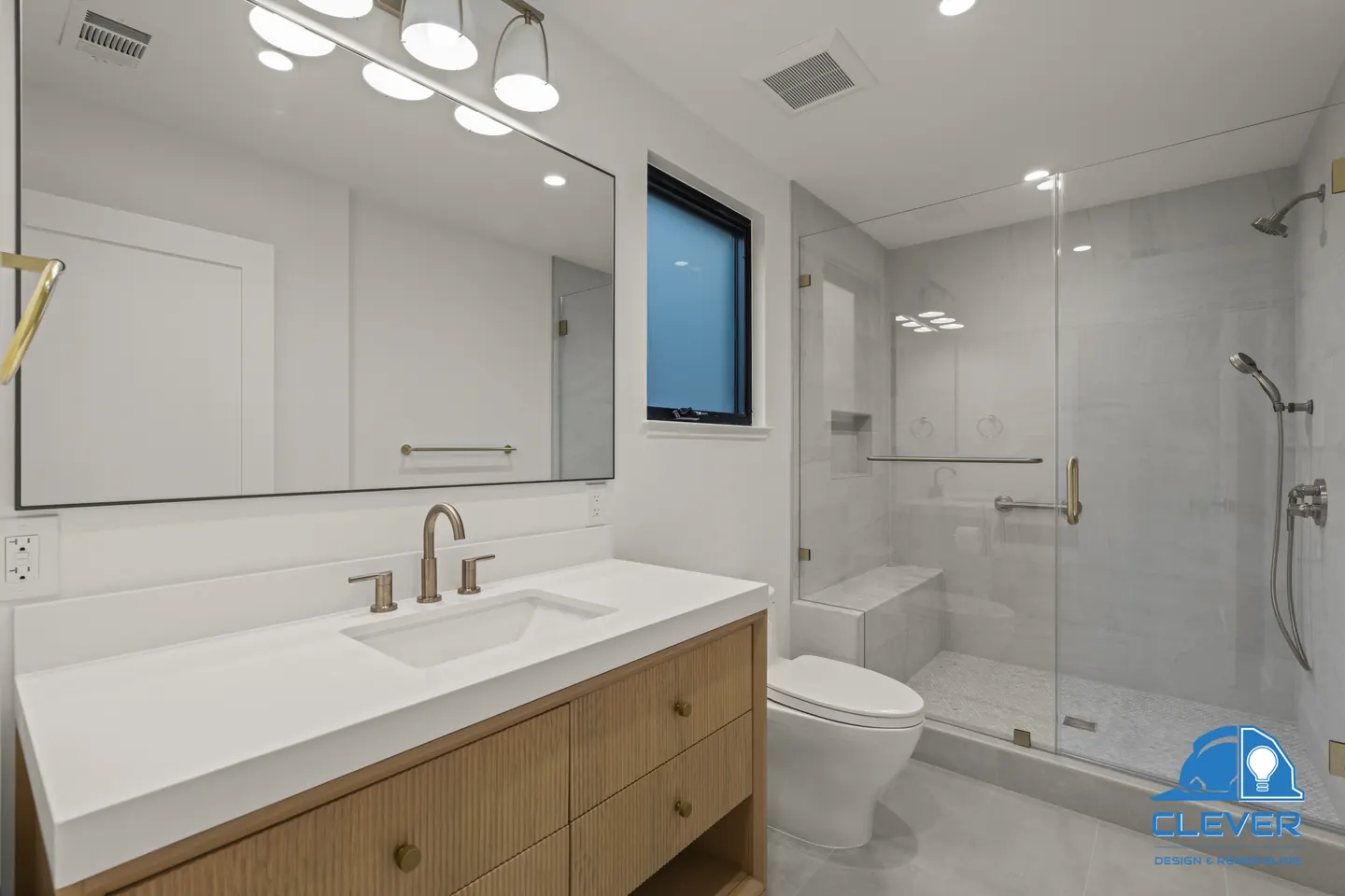 Bathroom with a fluted oak vanity, white quartz, brass faucet and a glass shower with a bench, whole-home remodel in Saratoga, CA